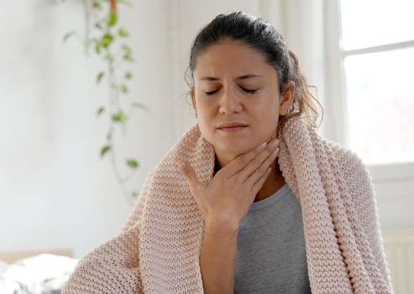 Women touching her throat with a blanket wrapped around