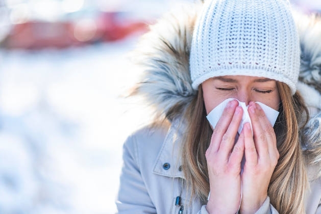 Woman blowing her nose into a tissue during Winter