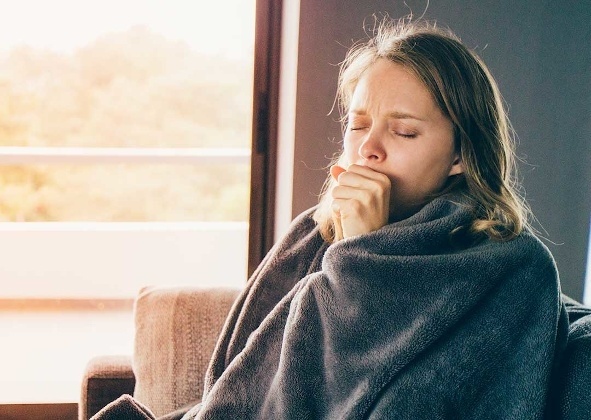 Women coughing with a blanket wrapped around herself